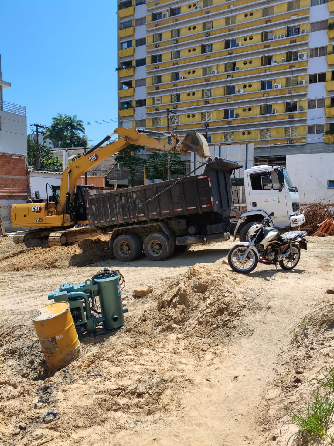 Escavadeira carregando caçamba em obra