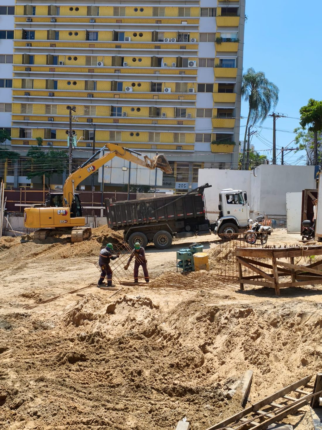 Equipe e escavadeira em obra de terraplanagem